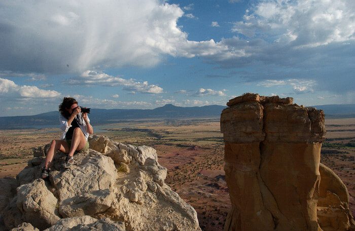 Woman taking a photo on top of a cliff