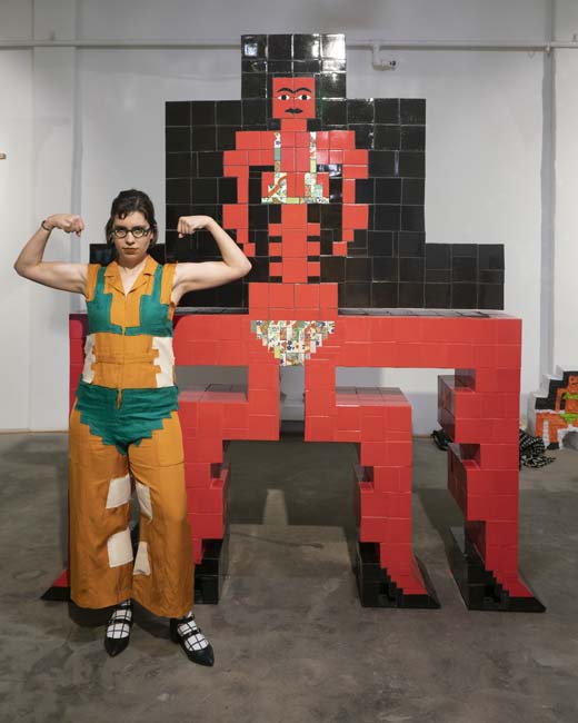 Artist Esther Elia posing with her monumental tiled sculpture of a bikini-clad Assyrian goddess.