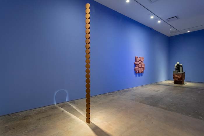 Installation view of work by Pedro Reyes with a steel sculpture reminiscent of Brancusi's Endless Column in the foreground.
