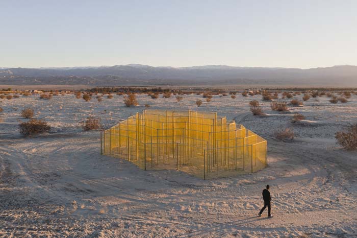 Installation of yellow-colored chainlink fence by Rana Begum for Desert X 2023.