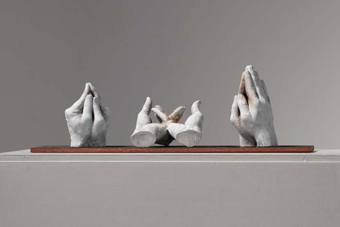 Three sculptures of hands forming the gestures of a Christian hand game