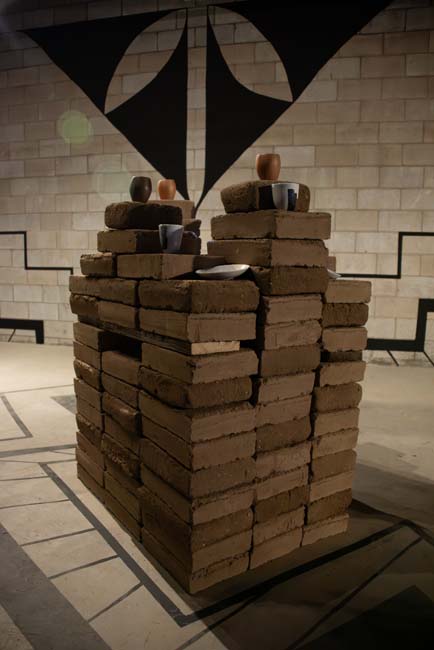 Stack of adobe bricks with ceramic vessels.