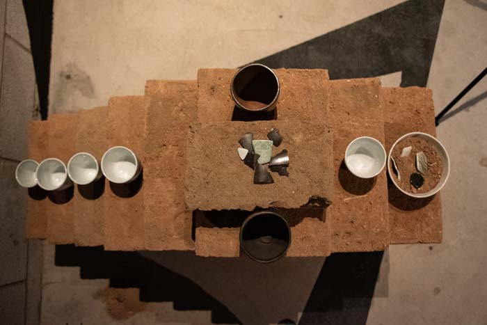 View from above over an adobe brick stack holding various ceramic vessels.