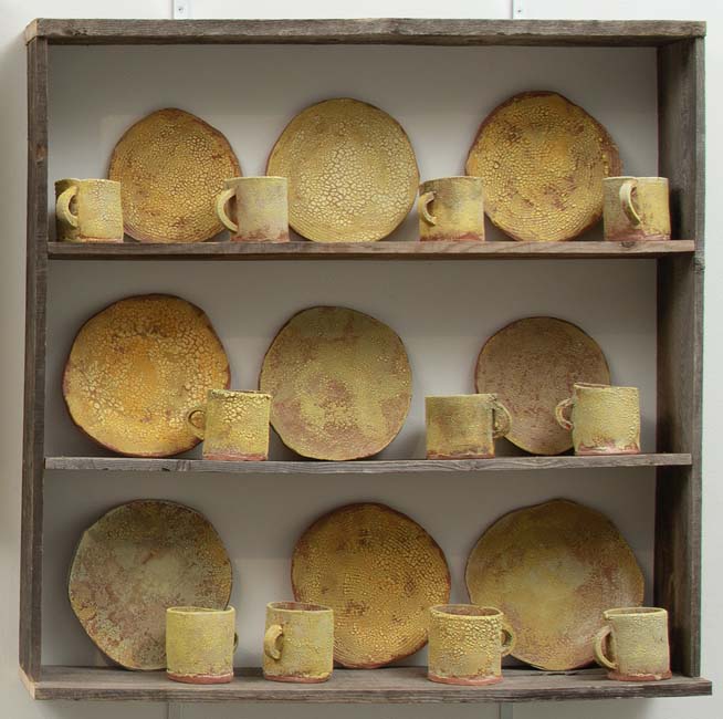 Collection of yellow colored terra cotta plates and mugs.