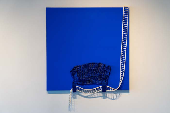 Bright blue square canvas with a blue painted chicharrón on the bottom half, holding up a white, ladder-like string, that extends to the top right corner of the canvas.