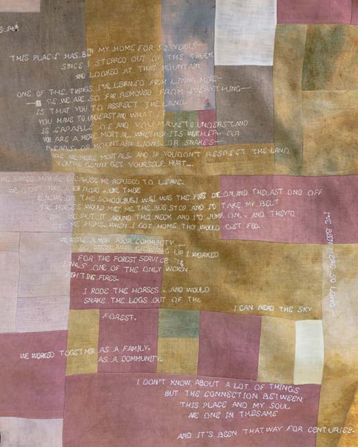 Patchwork quilt with a poem in white thread stitched into it, part of an eco art bioremediation project.