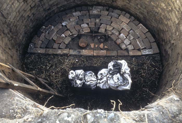 View looking down into a brick well, with a silver bundle placed inside.