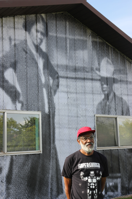 Chip Thomas poses in front of his mural of Charlie Glass