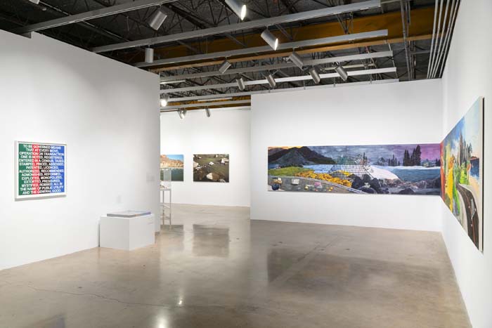 Installation view of an exhibition with long colorful landscapes on the wall.