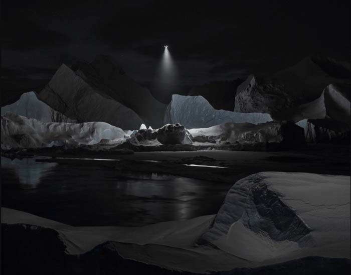 A beam of light emanating from a drone highlights a section of a glacier at night.