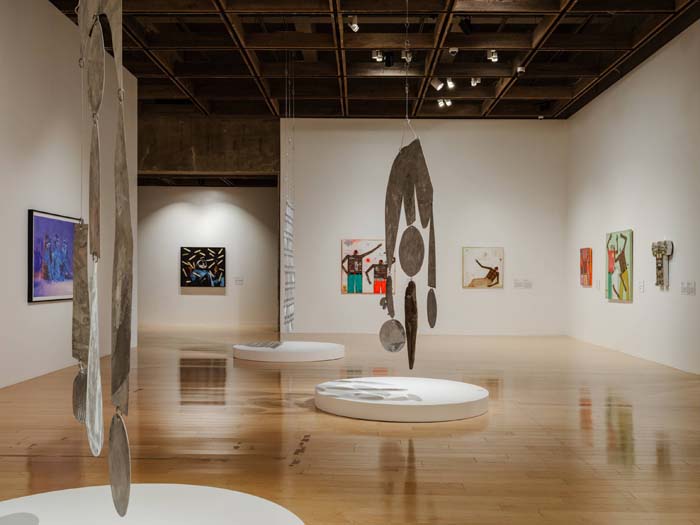 Installation view of the Palm Springs Art Museum with hanging modular sculptures and paintings.