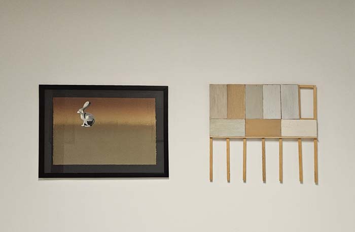 Two artworks by Patrick Kikut, a watercolor jack rabbit from of a scanned sticker from a National Parks souvenir store, cut-out and mounted on an oil-based monoprint ambiguously brown on the left, and a wall-mounted, model-scale billboard frame. 