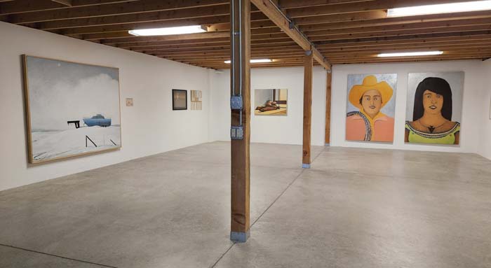 Installation view of Patrick Kikut, Bringing It All Back Home, at 5. Gallery in Santa Fe, with paintings of various sizes on the white walls of a room with wooden rafters and supports in the center of the room.