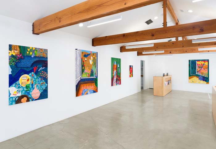 Installation view of colorful paintings by Kelly Lynn Jones, Tiny Tree, in a Palm Springs gallery with wooden beams and white walls.