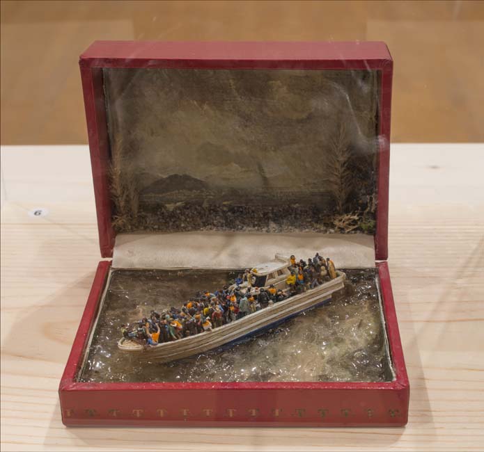 Crafted of minuscule objects in an old red jewelry box, a boat sit heavily in turbulent seas weighted down by figures.