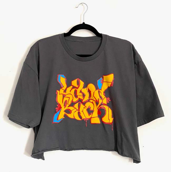 Southwest Gift Guide 2023: Grey crop tshirt with the words "Land Back" in yellow graffiti-style writing.