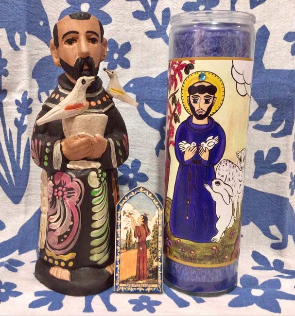 Southwest Gift Guide 2023: Painted wood Saint Francis of Assisi, Saint Francis retablo, Saint Francis candle on a blue-and-white tea towel.