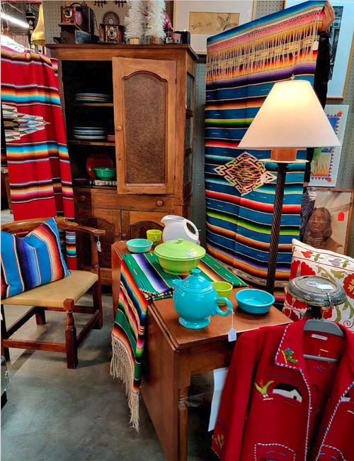 Southwest Gift Guide 2023: Santa Fe antique store interior, with colorful Native blankets, pottery, lamps, and furniture.