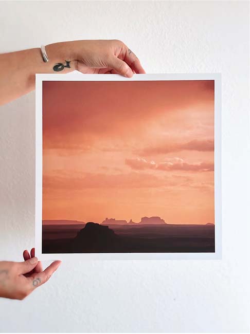 Southwest Gift Guide 2023: Hands holding up a photograph of an orange-tinted landscape with far-off horizon and distant rock formations.