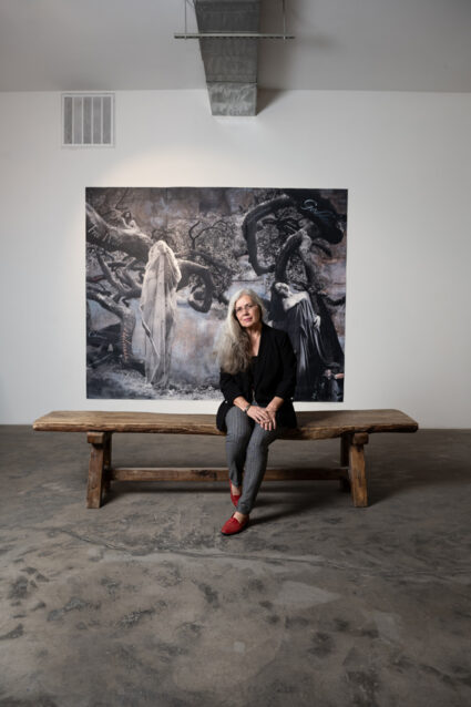 Delilah Montoya sitting in front of her work in the exhibition Divine Immanence at Sanitary Tortilla Factory, Albuquerque.
