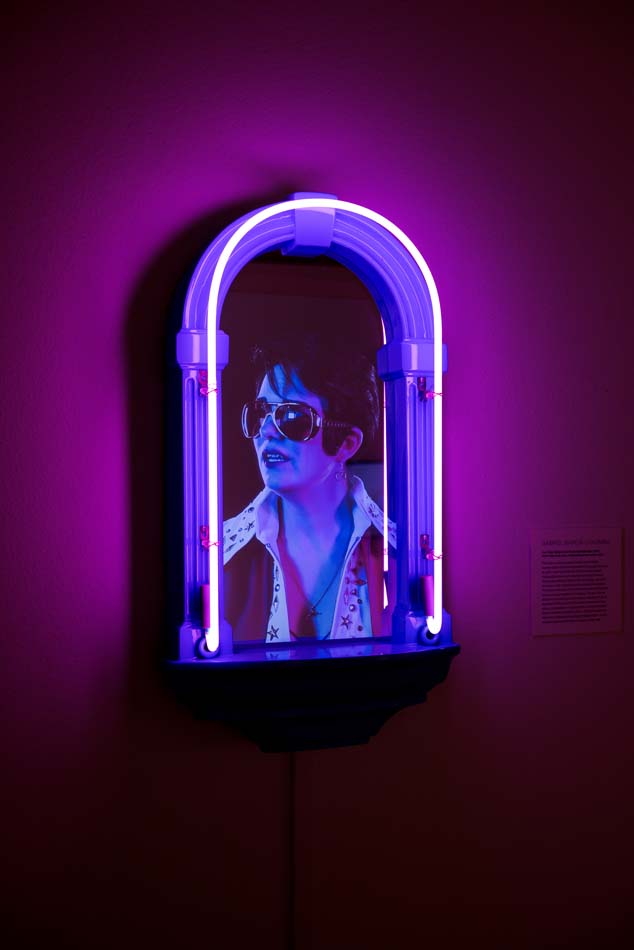 Elvis impersonator within an arched frame with purple neon.