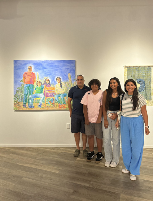 Perla Segovia and her family pose in front of the painting Pasadores at the Arizona Biennial 2023 at the Tucson Museum of Art