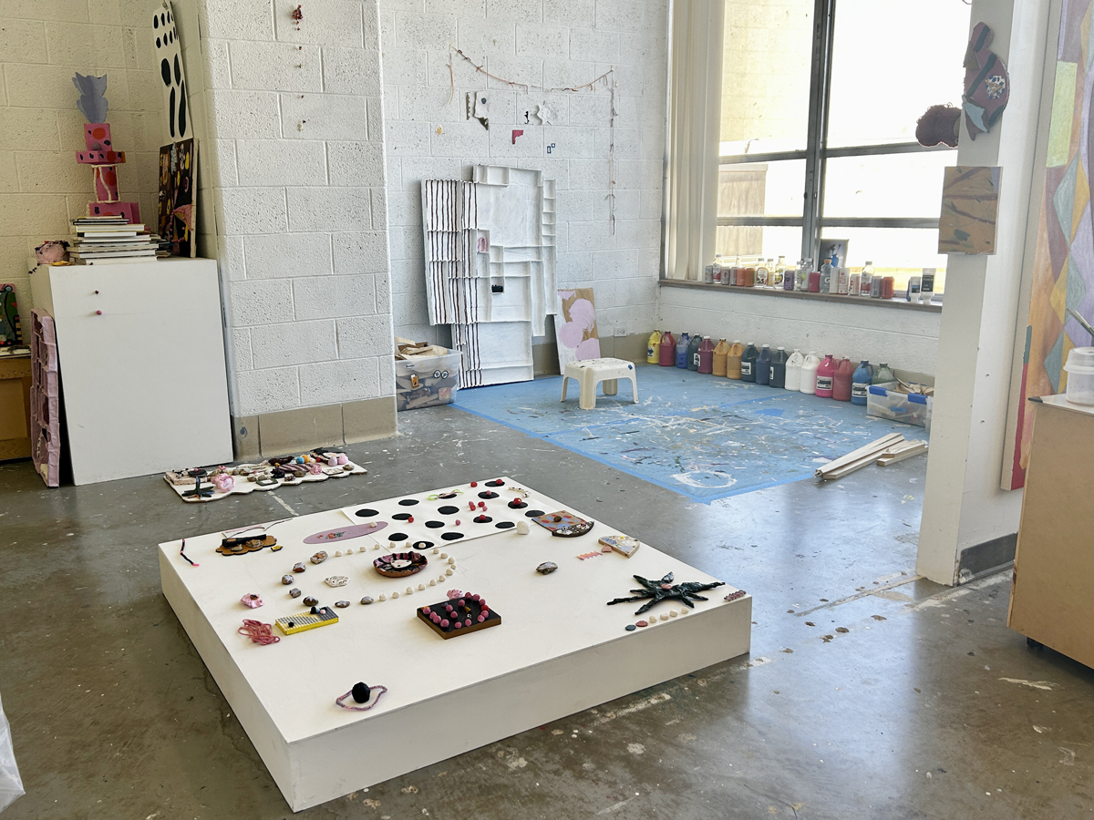 A low platform with a varied amount of small, rearrangeable objects inside of the studio of Claire Kennedy