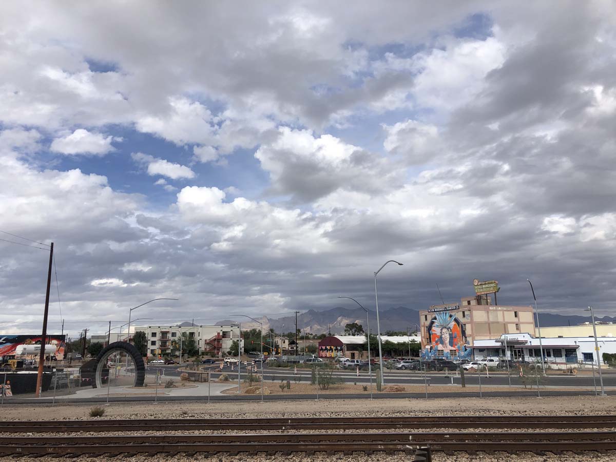 Train tracks running through downtown Tucson, Arizona, with cloudy sky. There have been changes to the downtown art scene due to construction and gentrification.