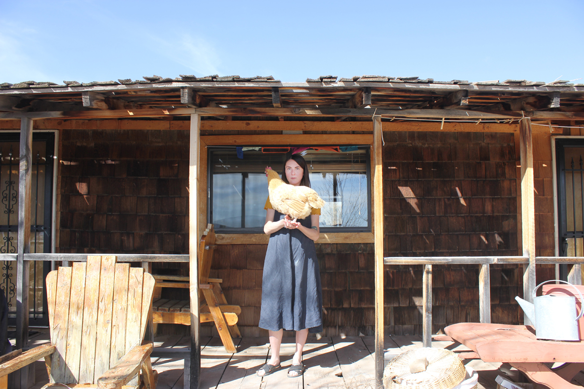 Emma Kemp stands on her porch holding a chicken at the Home of Truth. Photo by Emily Arntsen.