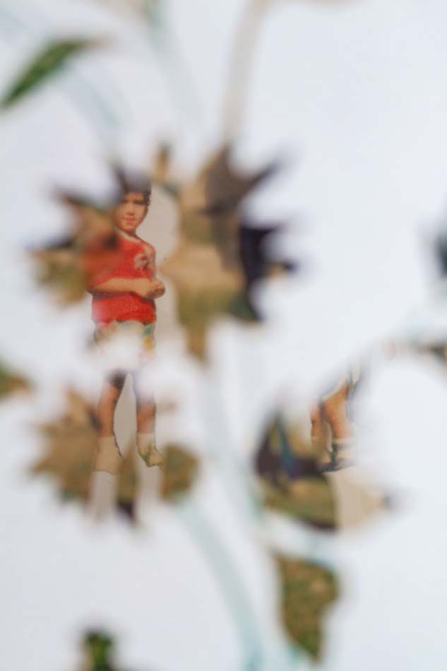 A photograph of a child wearing a red shirt partially obscured by white flower cut outs.