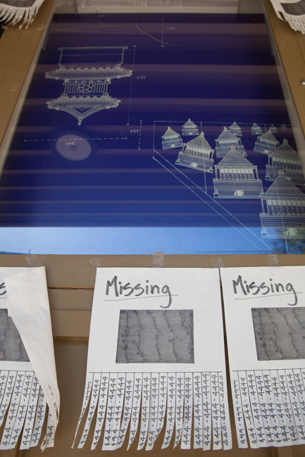 A close up view of Tailings by Jeannie Hua shows architectural renderings and sheets of paper with the word "Missing"