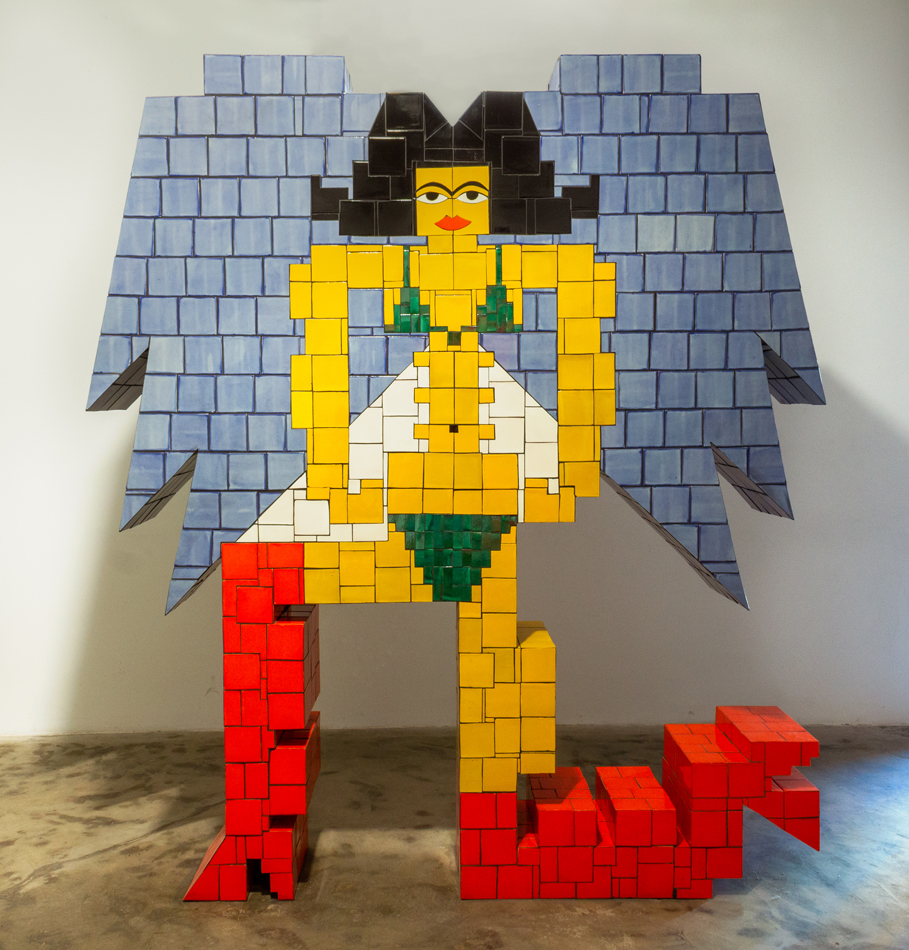 Malikta Protective Deity, Mexican tiles, mortar, grout, cement board, plywood. 8ft x 8ft x 3ft. 2023. A sculpture made out of red, yellow, green, white, blue, and black tiles. A female figure wearing red boots with blue angel wings.