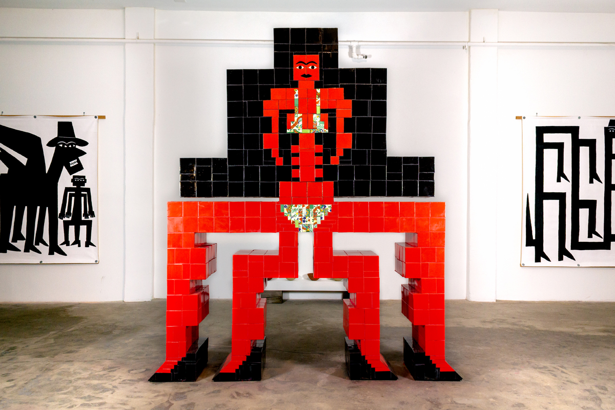 Esther Elia, Miztanta Protective Deity, 2023, Mexican tiles, epoxy, cement board, plywood, 8 x 8 x 3 ft. Large-scale sculpture made of red and black tiles showing a female figure with four legs and long black hair.