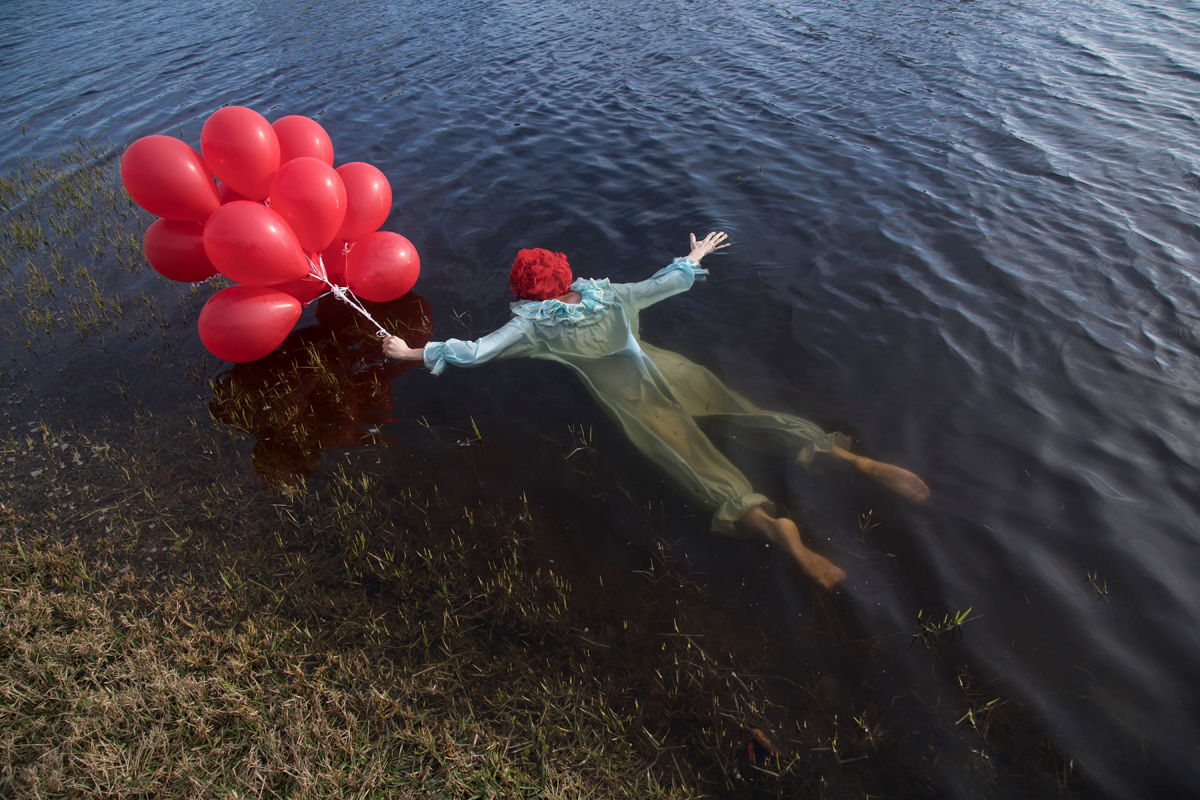 Laura Shill dresses as a clown and floats face down in water