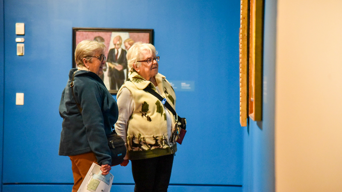 Two women stand in front of a Clarence Shivers work