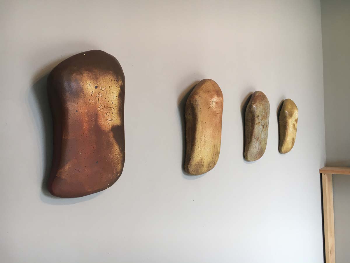 Four ceramic wall hangings by Bill Gilbert, roughly square shaped with rounded edges.