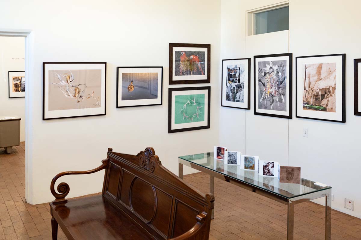 Installation view at Andrew Smith Gallery in Tucson of multiple framed prints by Duwawisioma (Victor Masayesva Jr.), with a table and a bench in the middle of the room.