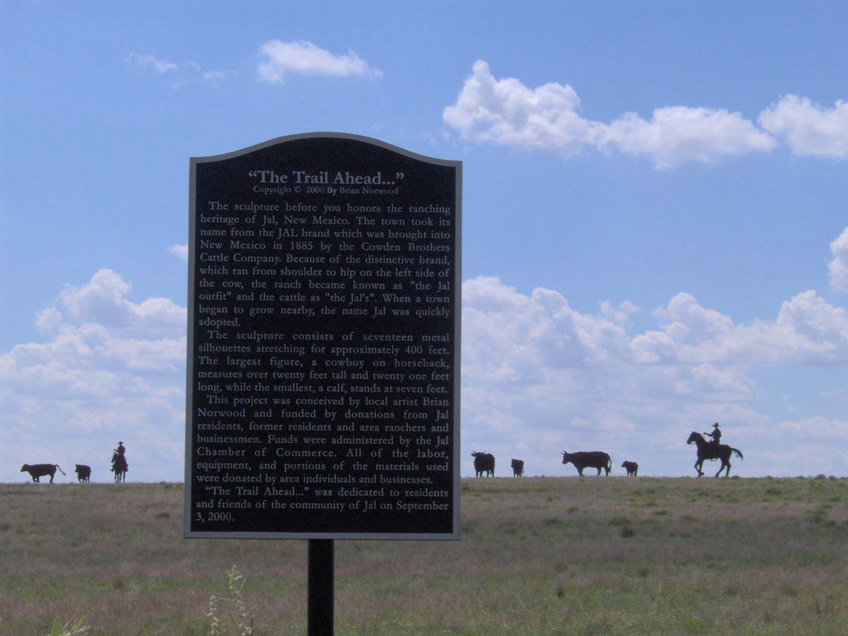 Roadside marker with text about the steel sculpture of a cattle drive by Brian Norwood.