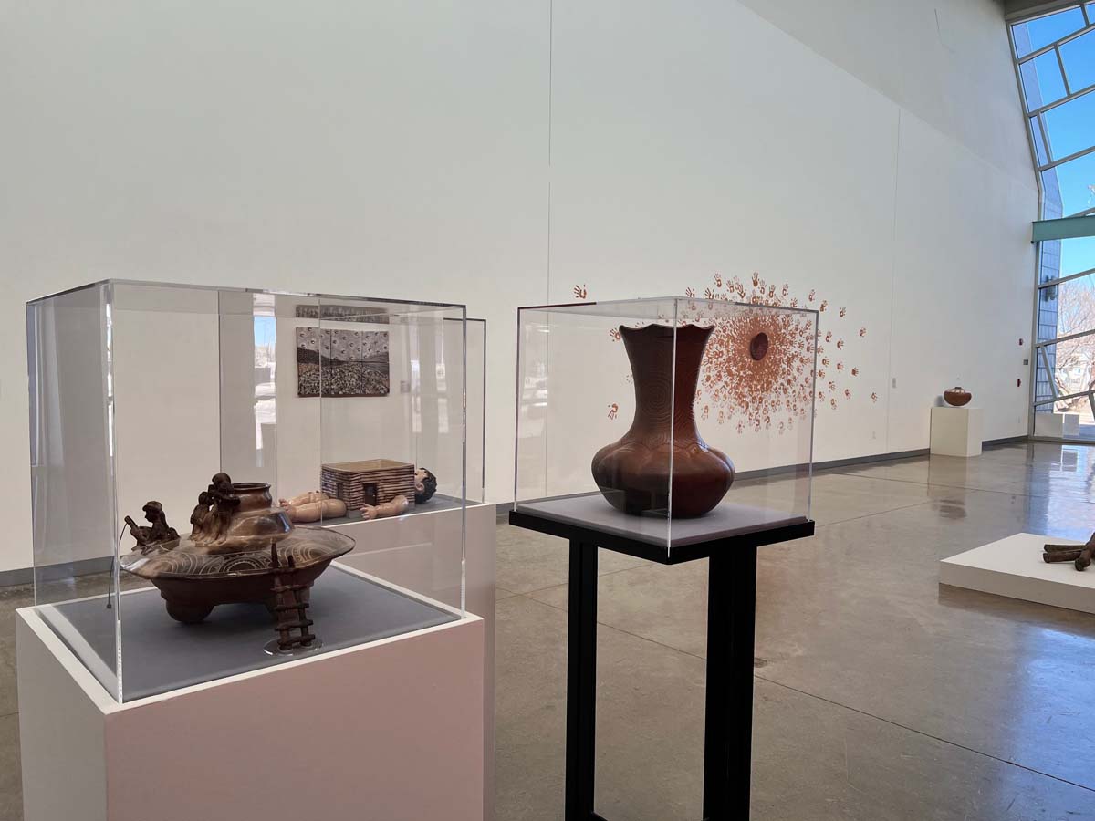 Installation view of Belonging: Contemporary Native Ceramics from the Southern Plains, with ceramic vessels in vitrines in the foreground, a large-scale ceramic sculpture in the background.