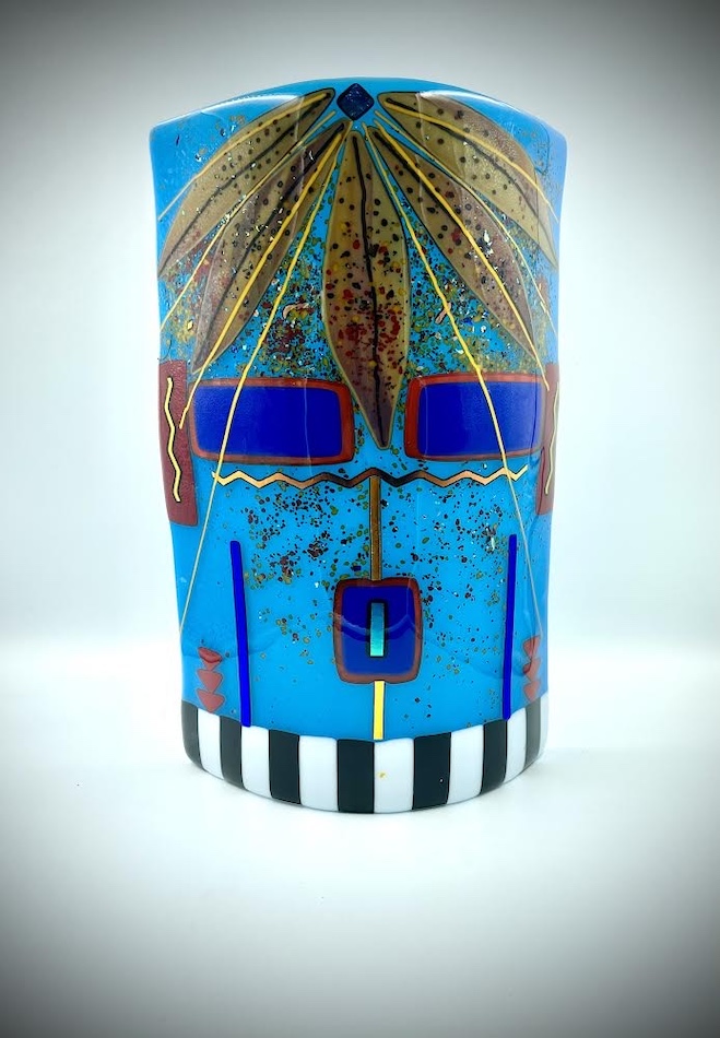 Fused glass cylinder with abstracted face of water deity.