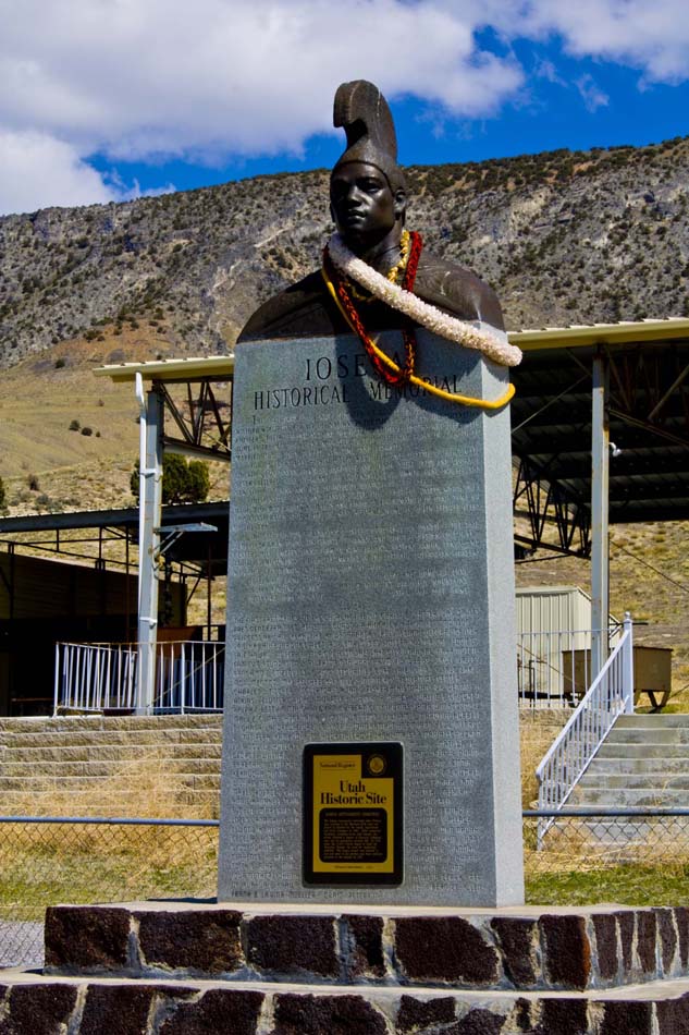 Monument of a bronze bust of a man with several leis draped over his shoulder, overlooking Iosepa, Utah cemetery, Skull Valley, Utah