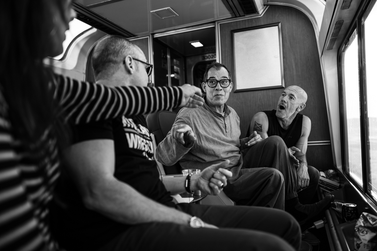 Four artists from the railroad-themed art exhibition The Other Side of the Tracks chat inside a train car.