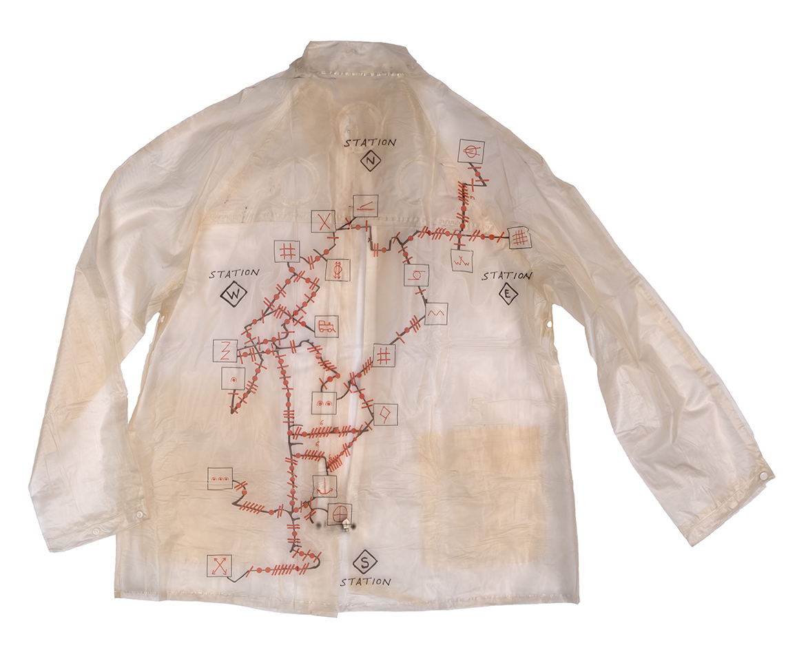 Rain poncho with an experimental performance score printed across it, resembling a map of a railway line.