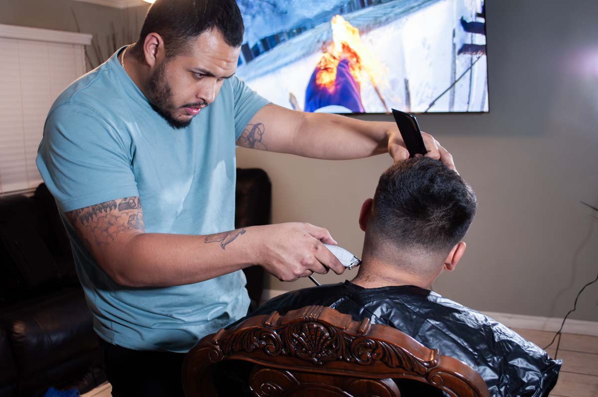 Photo of a man giving another man a haircut in a barber shop.