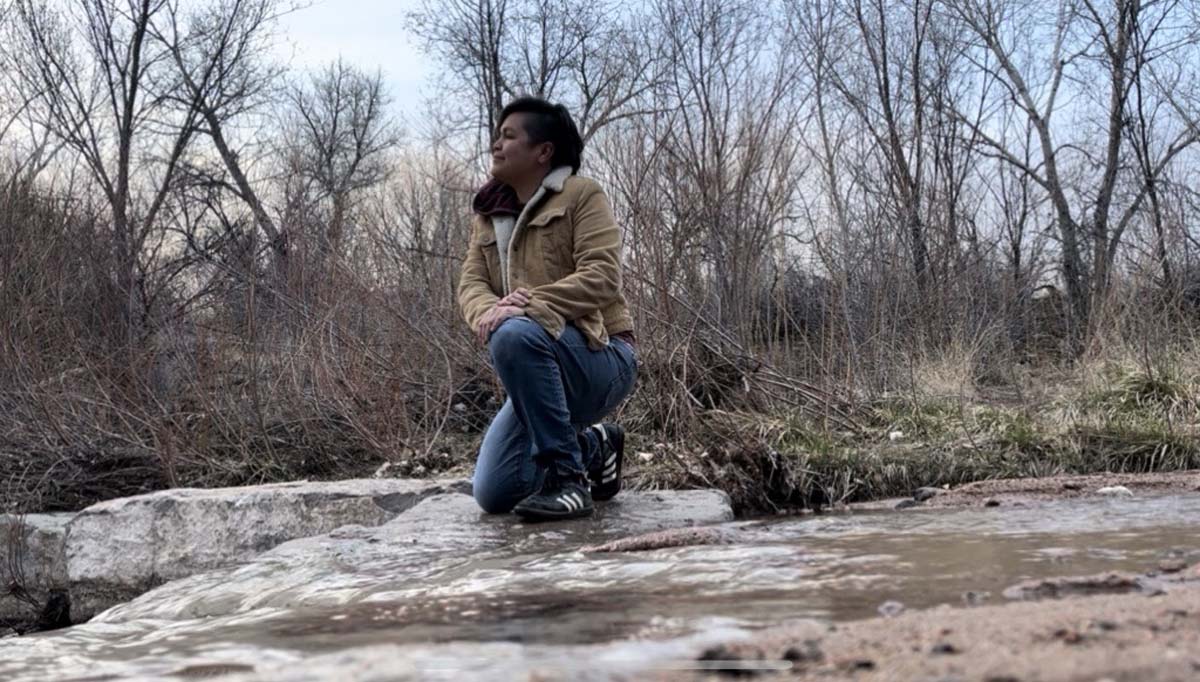 Ángel Faz crouching on the riverbank of the Santa Fe River