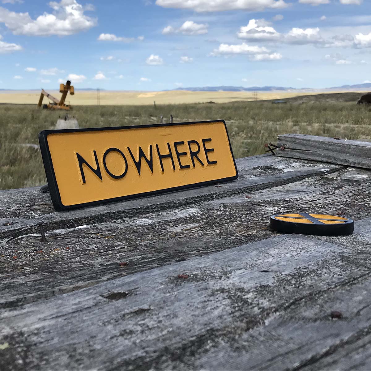 An art installation featuring a black-and-yellow sign that reads "NOWHERE."