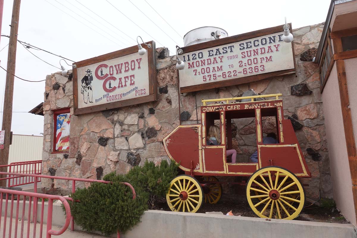 Exterior of the Cowboy Cafe with an antique red carriage with yellow wagon wheels outside.