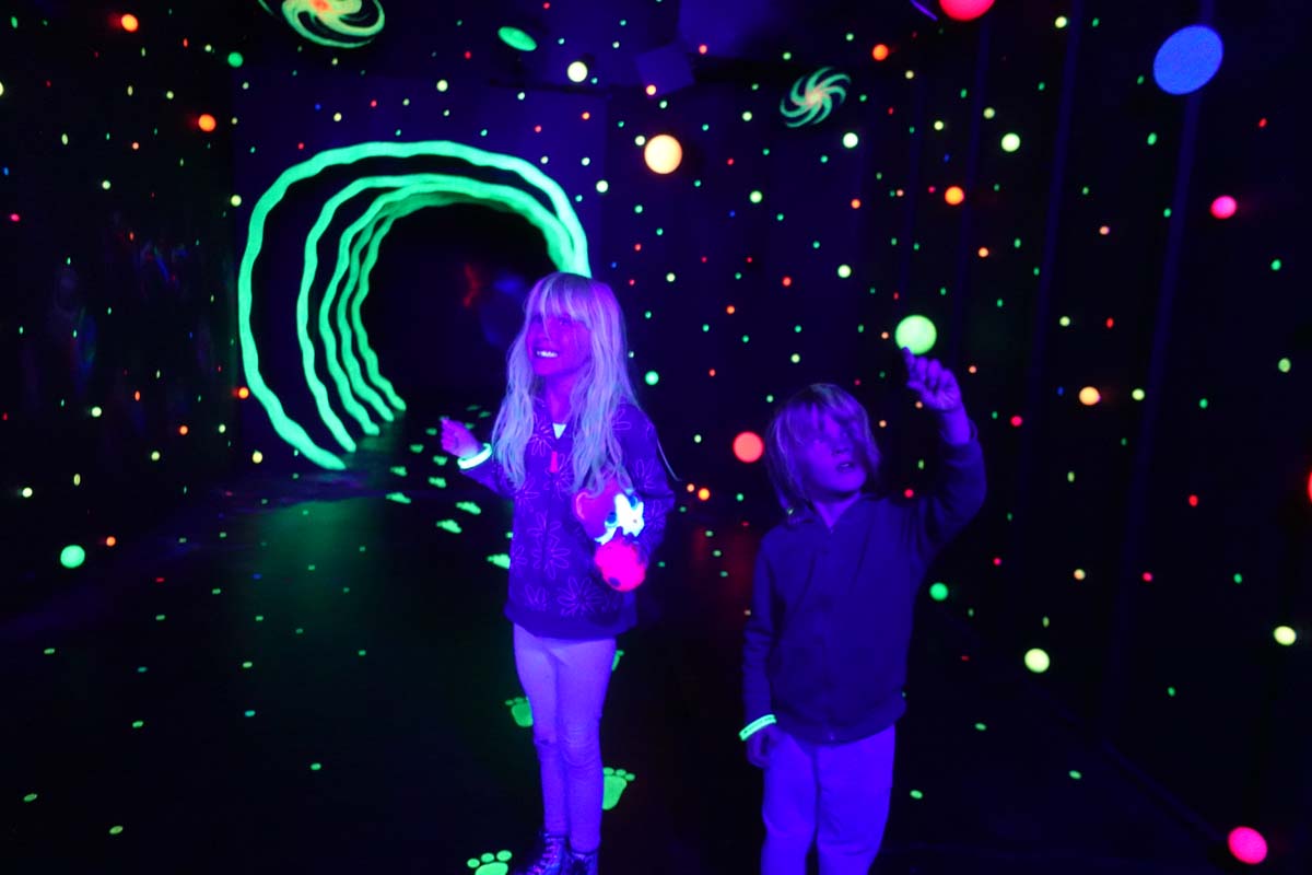 Two children inside the Roswell UFO Spacewalk and Gallery black light environment.