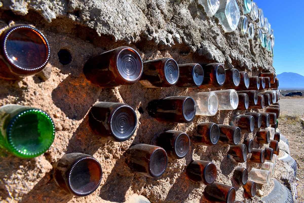 Bottles stud a wall made from earth in this detail image of a structure by Earthship Biotecture, one of several New Mexico roadside attractions featured in this story.