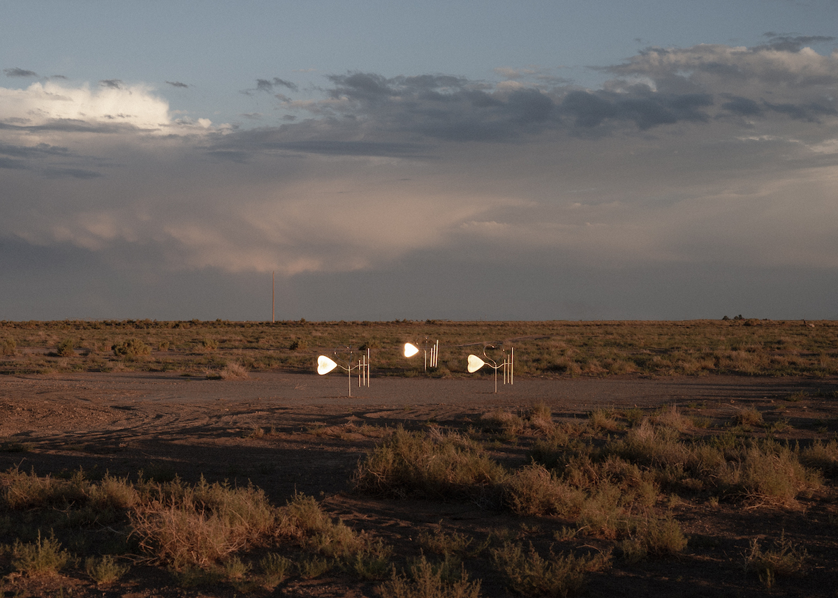 An art installation of three metallic sculpture forms dwarfed by a sprawling Southwestern vista.